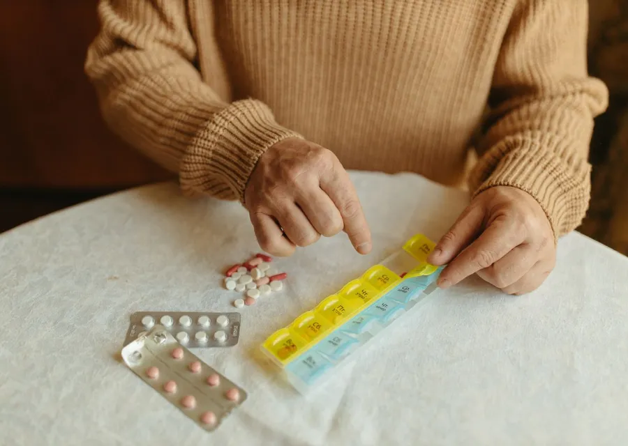 Persona mayor organizando sus medicinas en un pastillero semanal