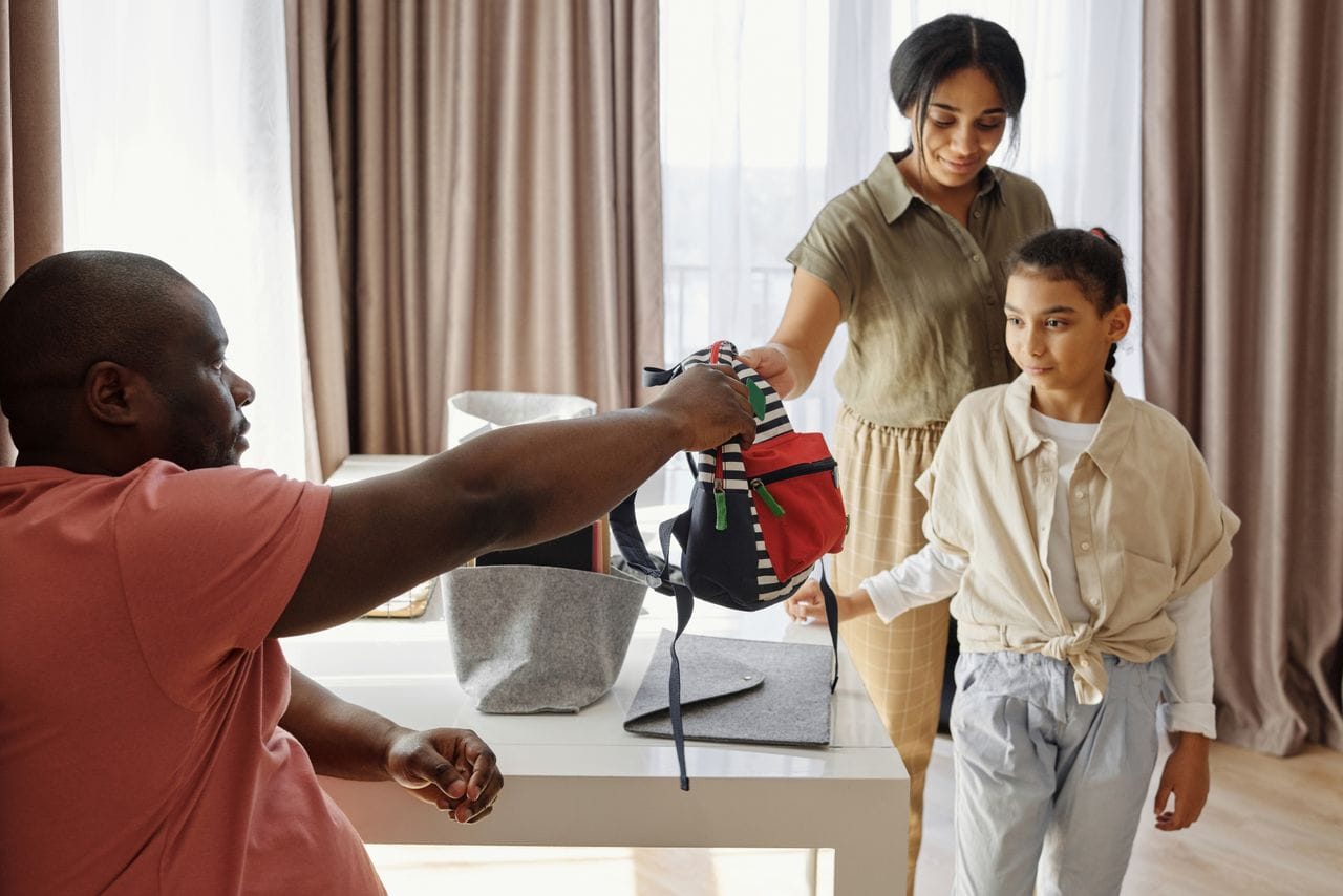 Padres preparando la mochila escolar de su hija para el regreso a clases